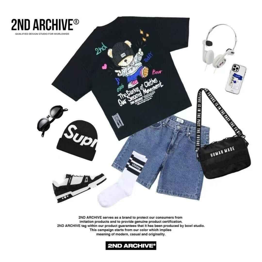 Black teddy bear graphic tee, denim shorts, beanie, sneakers, and accessories flat lay.