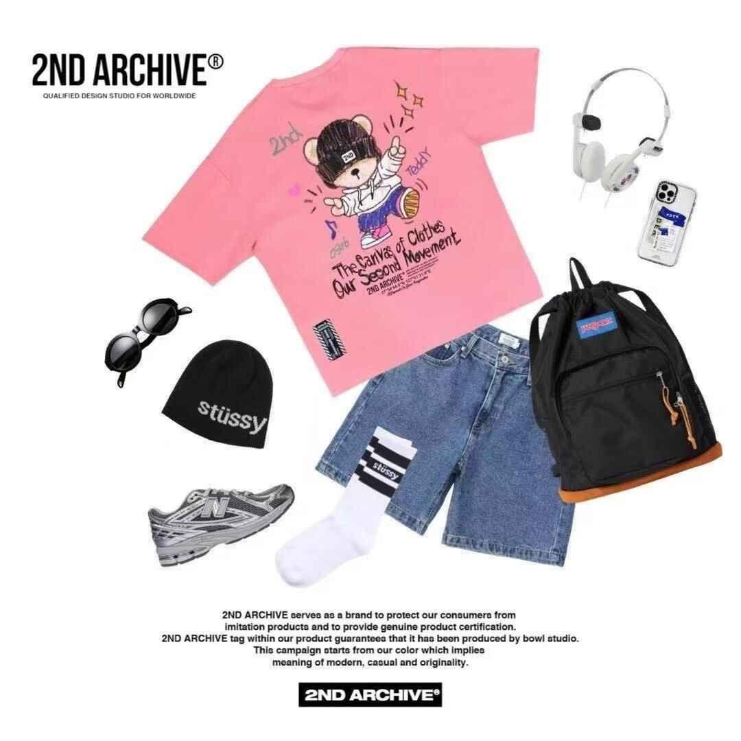 Flat lay of streetwear outfit with pink teddy bear graphic tee, denim shorts, black backpack, black beanie, sunglasses, grey sneakers, white socks, headphones, and smartphone.