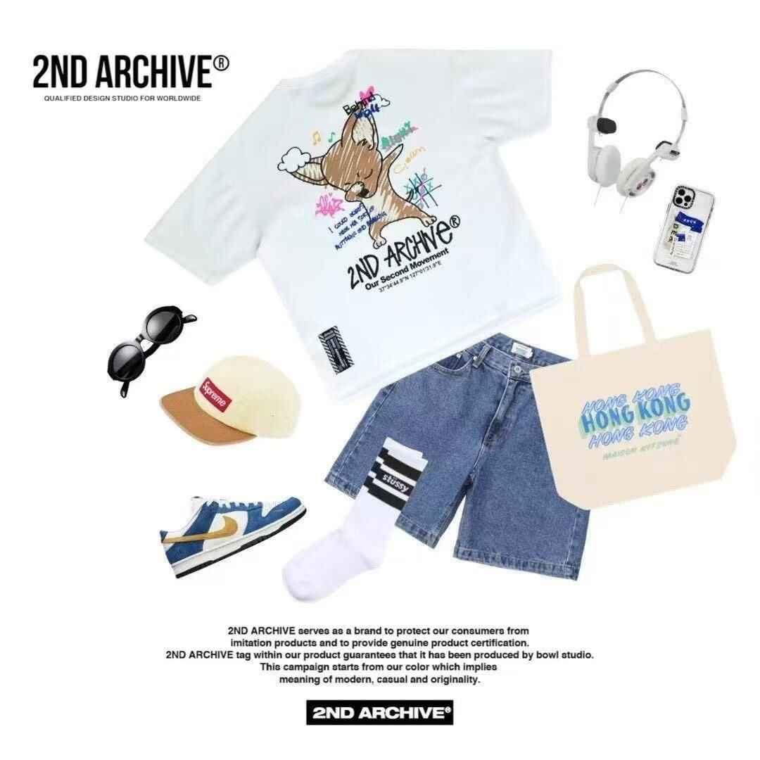 Flat lay of casual summer outfit with graphic white t-shirt, denim shorts, blue sneakers, cream tote bag with &
