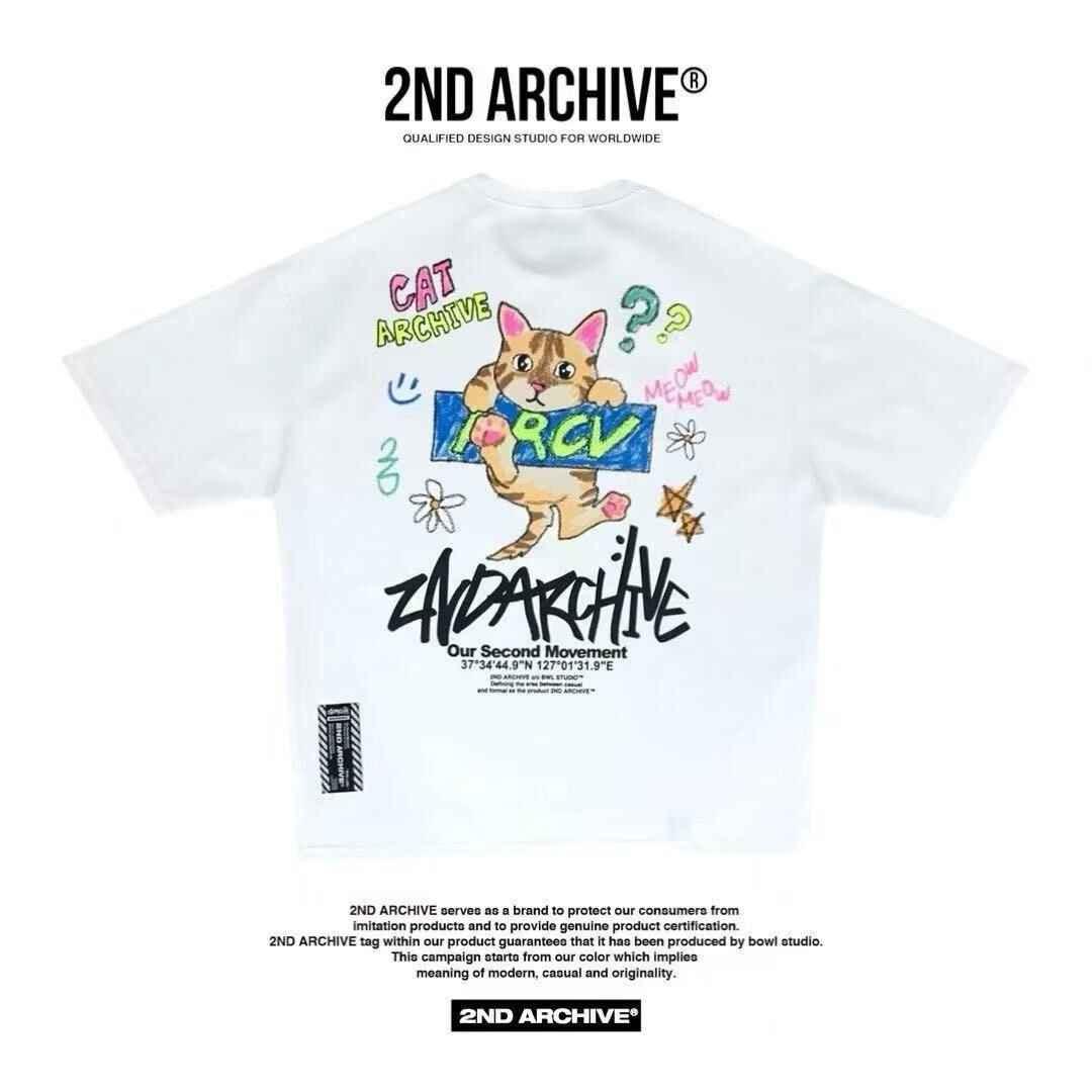 White graphic tee featuring a cartoon cat illustration, colorful doodles, and bold &