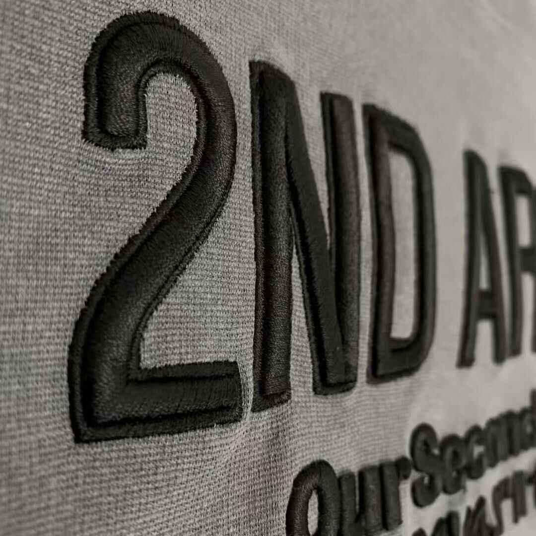 Close-up of black embossed 2ND ARCHIVE logo on grey textured short sleeve t-shirt