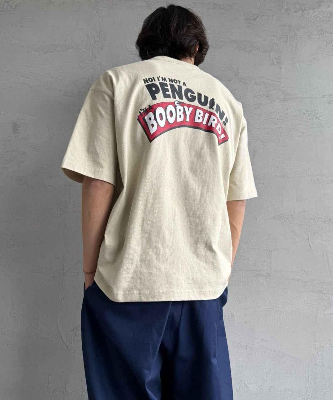 Back view of a person wearing a beige graphic t-shirt with &