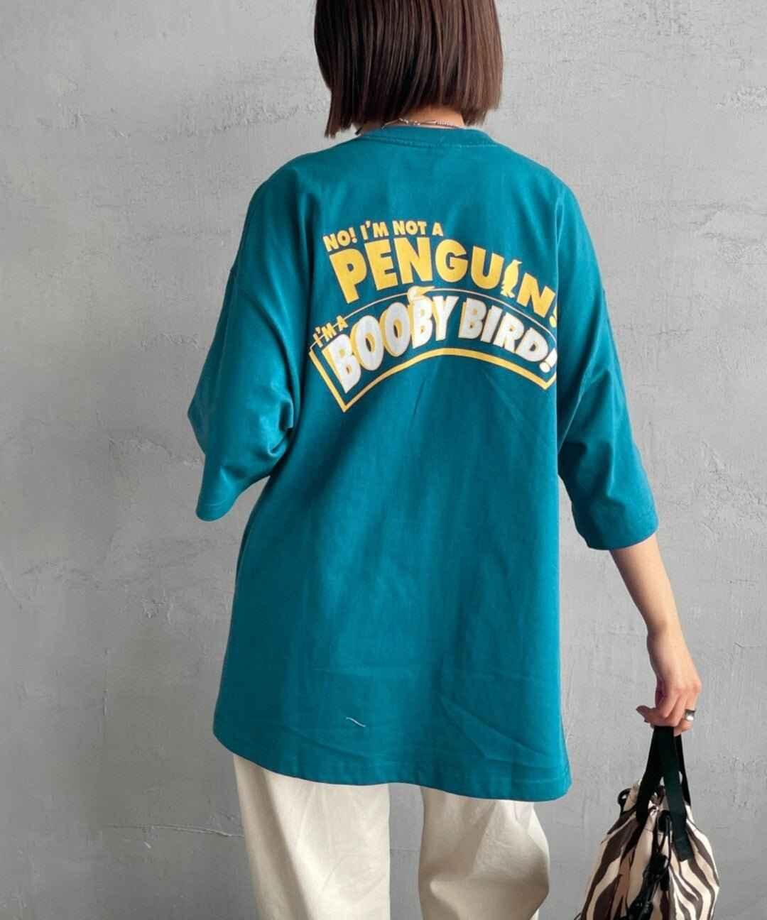 Back view of a blue oversized tee with yellow &