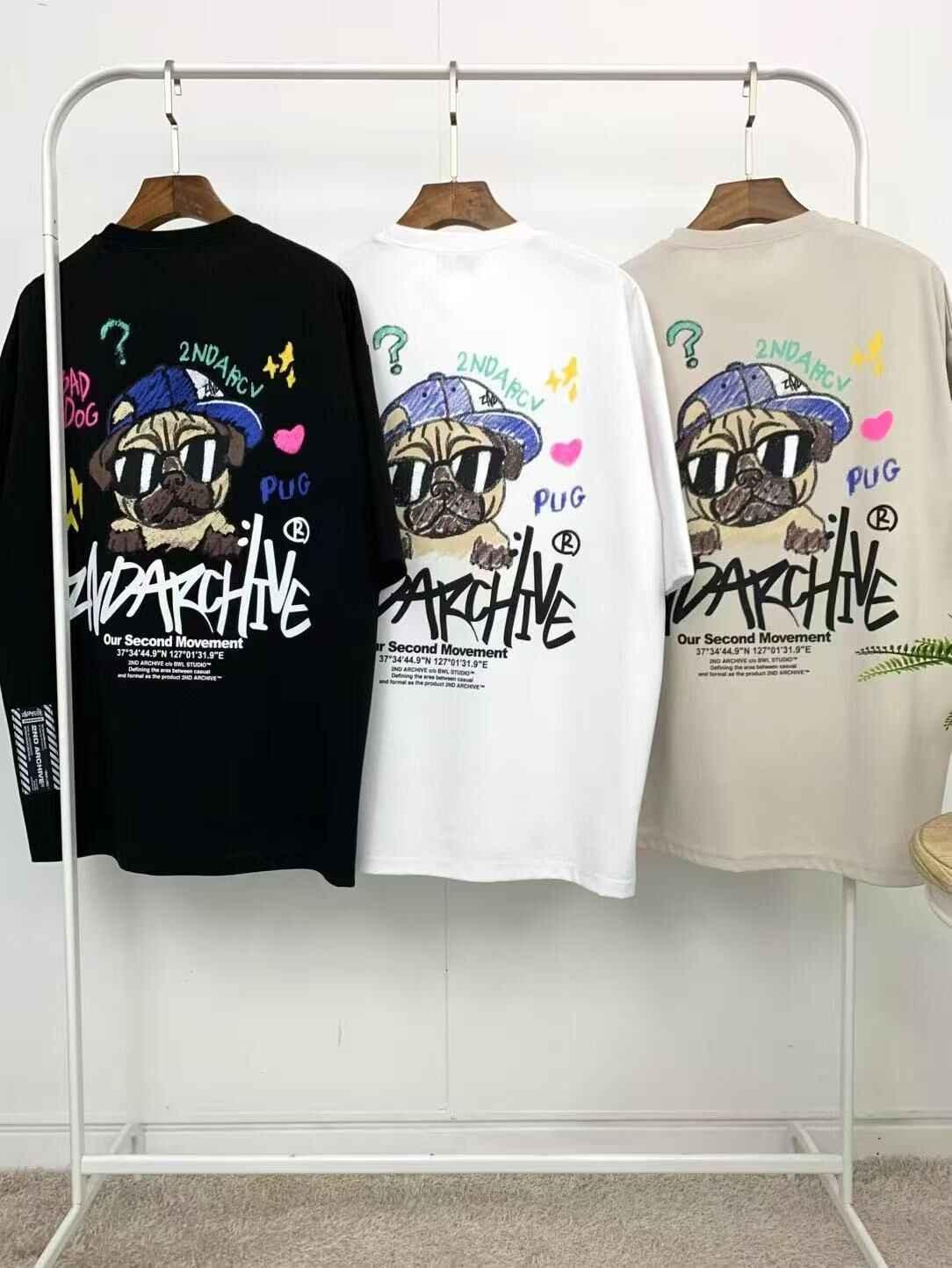 Three graphic t-shirts with cartoon pug dog design and colorful lettering on a clothing rack