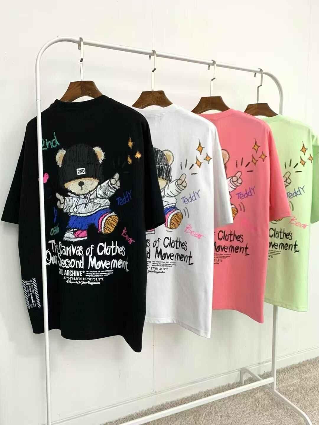 Colorful graphic t-shirts with teddy bear and text design hanging on a clothing rack.