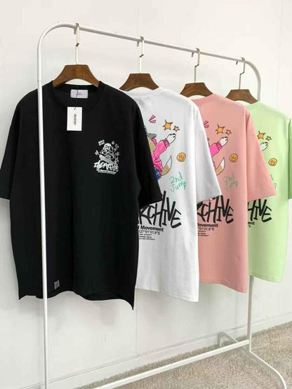 Four oversized graphic t-shirts in black, white, pink, and light green on a clothing rack, featuring cartoon dog and crayon art designs.
