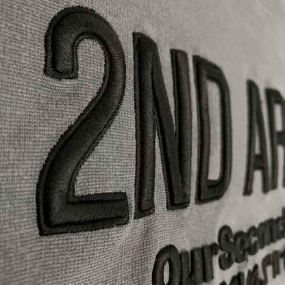 Close-up of black embossed 2ND ARCHIVE logo on grey textured short sleeve t-shirt