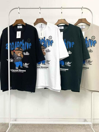 Four 2nd Archive crayon bear graphic t-shirts in black, white, green, and beige on hangers.