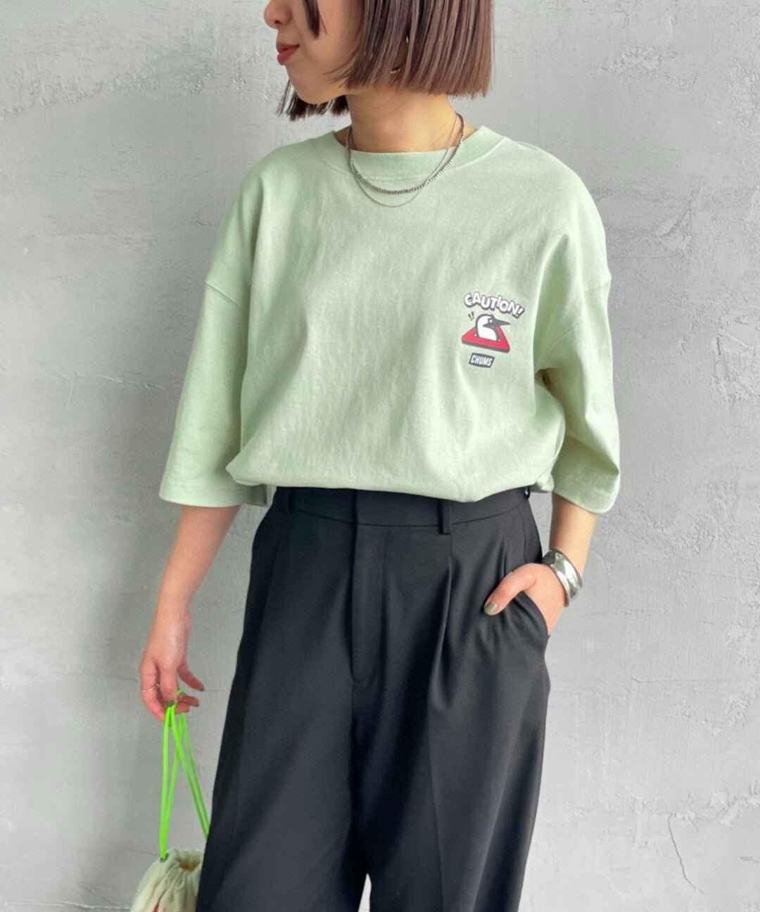 Woman wearing light green booby bird graphic t-shirt and black high-waist pants