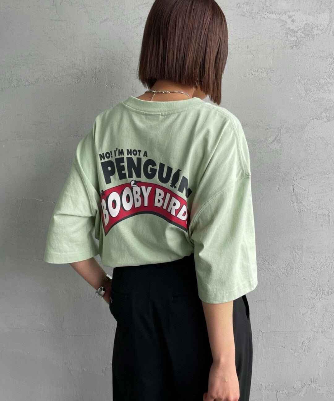 Woman wearing light green oversized T-shirt with &