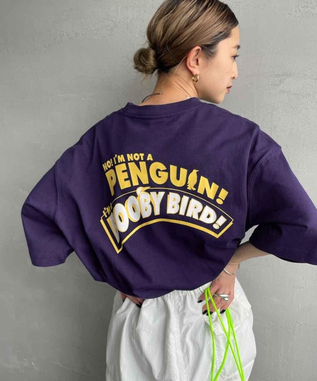Woman wearing dark purple t-shirt with bold yellow &