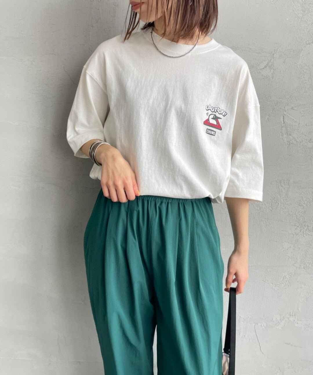 Woman wearing a white graphic oversized T-shirt with casual green pants, stylish streetwear outfit