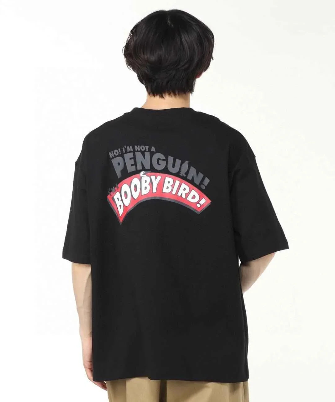 Back view of a person wearing a black oversized t-shirt with &
